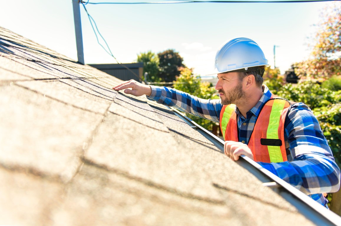 An image of a man inspecting a roof for roofing services